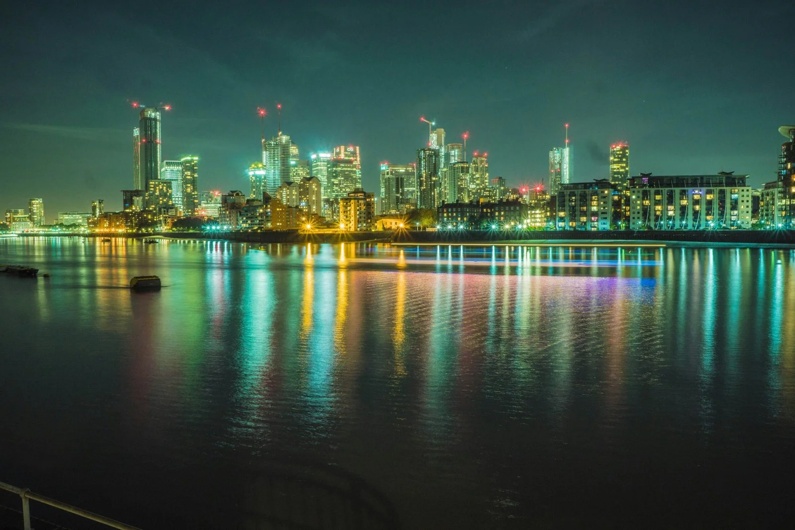 city skyline across body of water during night time